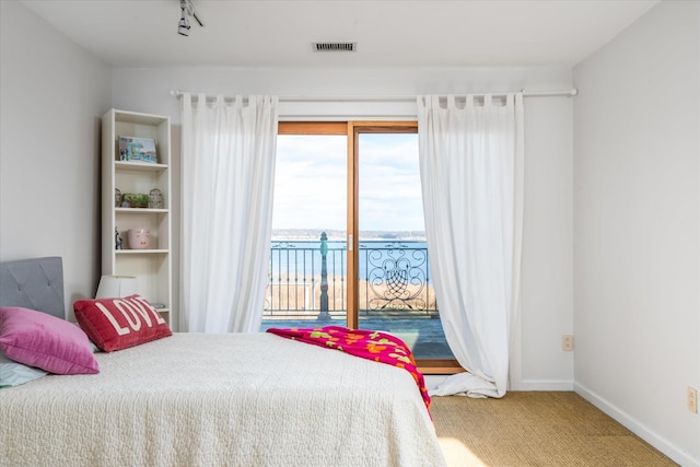 bedroom featuring carpet flooring, access to outside, and a water view