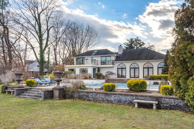 back of property with a lawn, a balcony, and a patio