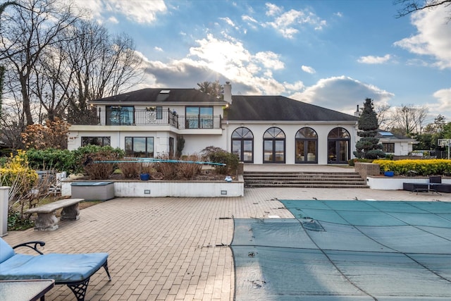 back of house featuring a patio, a balcony, and a covered pool