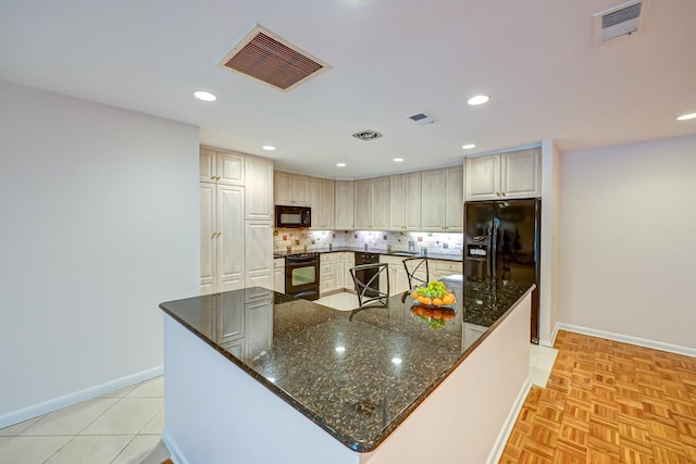 kitchen with decorative backsplash, a kitchen island, dark stone countertops, and black appliances