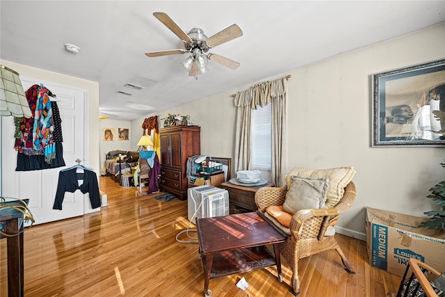 living area with wood-type flooring and ceiling fan