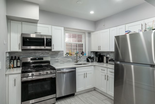 kitchen with backsplash, sink, white cabinetry, and stainless steel appliances