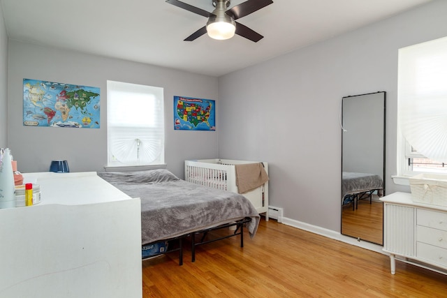 bedroom with hardwood / wood-style floors, a baseboard radiator, and ceiling fan