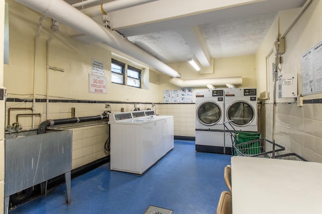 laundry area featuring washing machine and dryer, sink, tile walls, and a textured ceiling