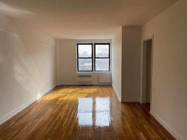 spare room featuring radiator heating unit and wood-type flooring