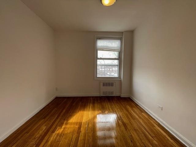 unfurnished room with radiator and dark hardwood / wood-style floors