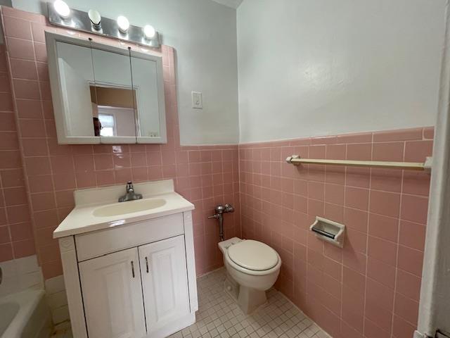 bathroom with tile patterned flooring, vanity, tile walls, and toilet