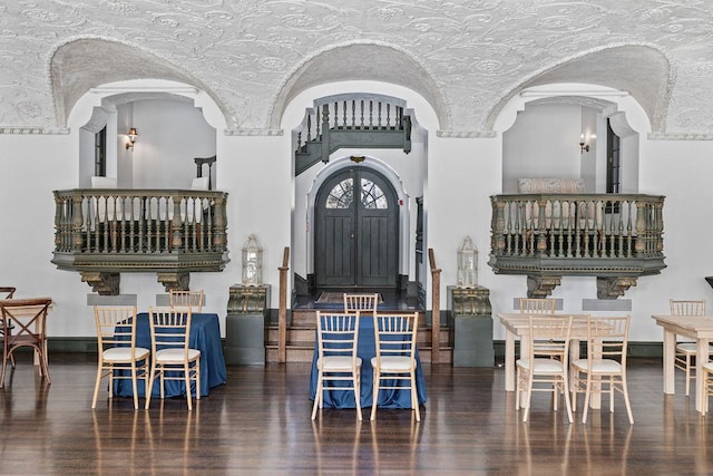 dining space featuring arched walkways, dark wood-type flooring, and baseboards