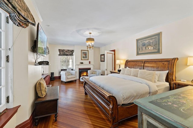 bedroom featuring ornamental molding, dark wood finished floors, a lit fireplace, and baseboards