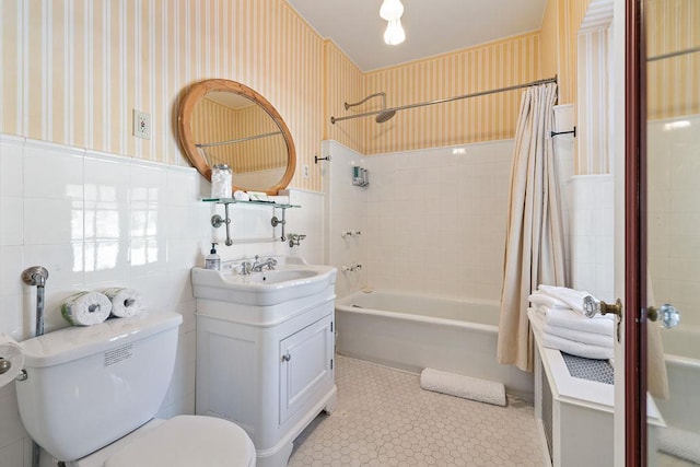 full bath with wainscoting, tile walls, toilet, and wallpapered walls