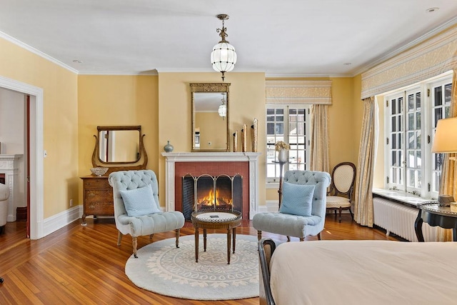 living area featuring baseboards, radiator, wood finished floors, crown molding, and a fireplace