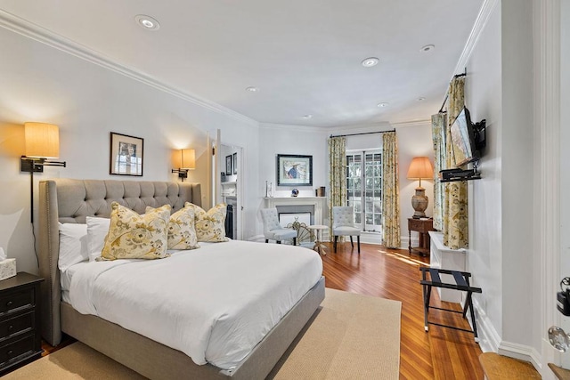 bedroom with ornamental molding, a fireplace, wood finished floors, and baseboards