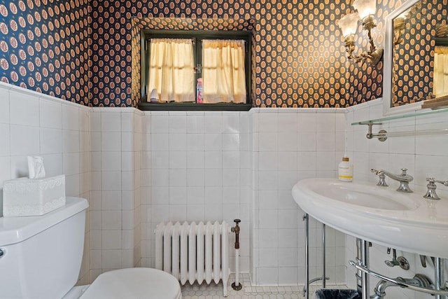 half bathroom with toilet, wallpapered walls, radiator heating unit, and wainscoting