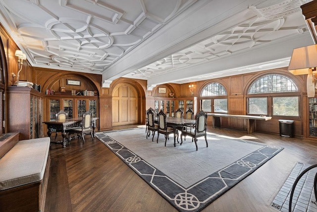 dining space featuring dark wood-style floors, coffered ceiling, and wood walls