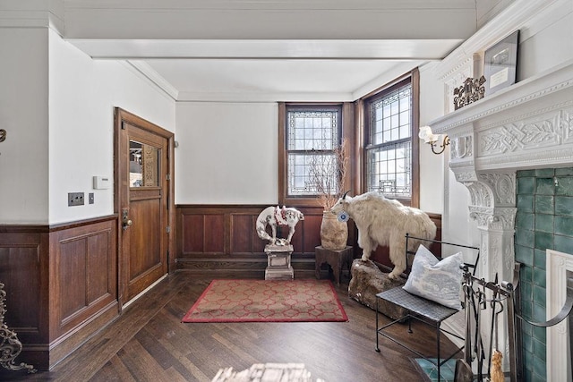 interior space with crown molding, a fireplace, dark wood finished floors, wainscoting, and beamed ceiling