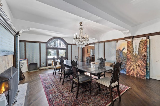 dining space with dark wood-style flooring, a high end fireplace, and an inviting chandelier