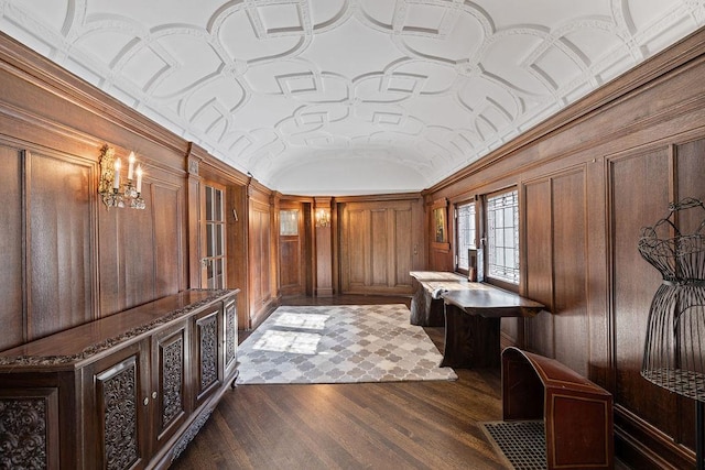 foyer entrance featuring vaulted ceiling, dark wood-type flooring, and wood walls