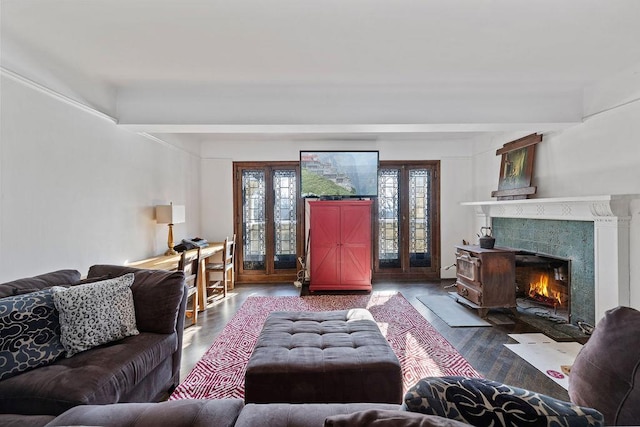 living area featuring wood finished floors, french doors, and a fireplace with flush hearth