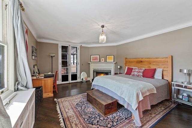 bedroom with a warm lit fireplace, access to outside, dark wood finished floors, and crown molding