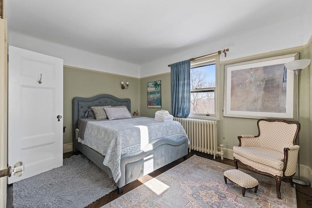 bedroom with radiator heating unit, baseboards, and wood finished floors