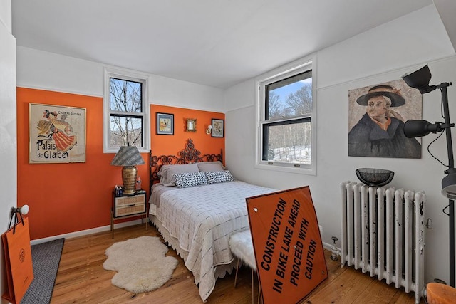 bedroom with baseboards, light wood finished floors, and radiator