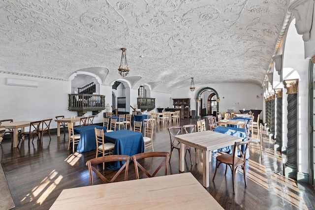 dining room featuring baseboards, arched walkways, lofted ceiling, dark wood-style floors, and a wall unit AC