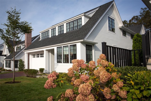 view of front facade with a garage, a front lawn, and a shingled roof