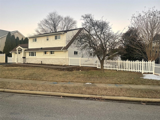 traditional-style home featuring fence, a front lawn, and stucco siding