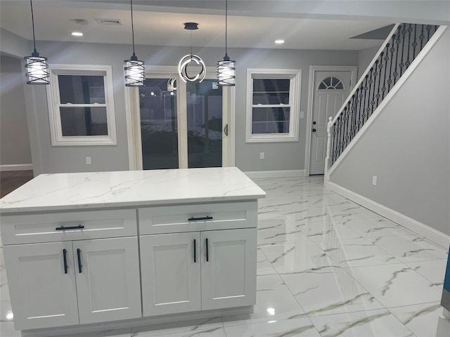 kitchen with light stone countertops, white cabinets, and pendant lighting