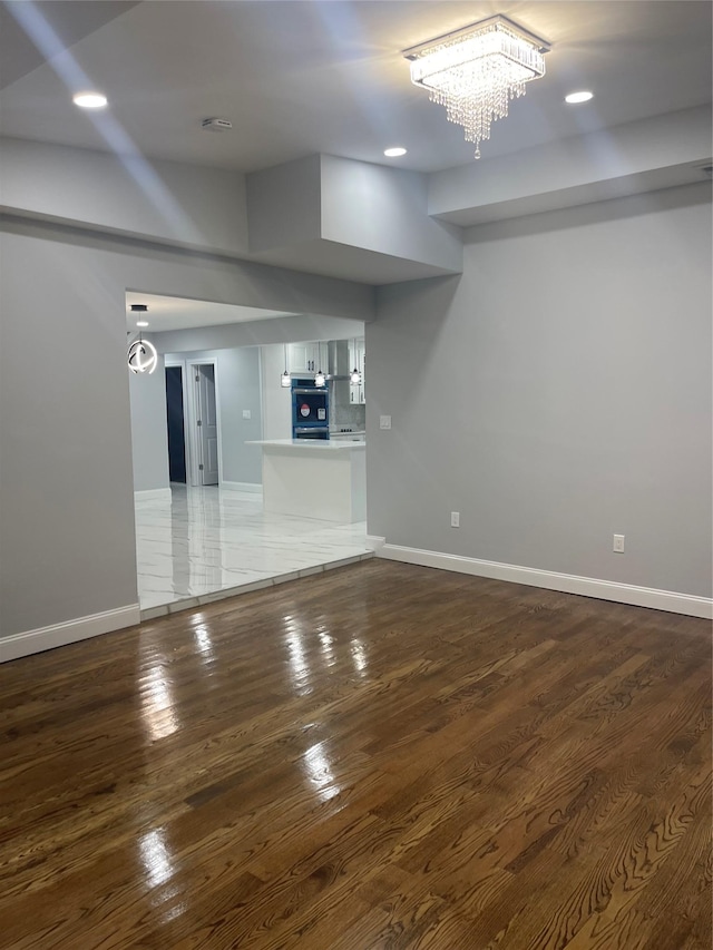 unfurnished living room featuring dark hardwood / wood-style floors and an inviting chandelier