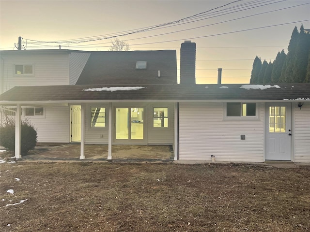 back house at dusk with a patio area