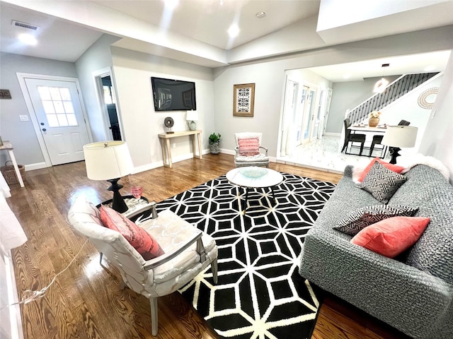 living area featuring wood finished floors, visible vents, baseboards, and stairs