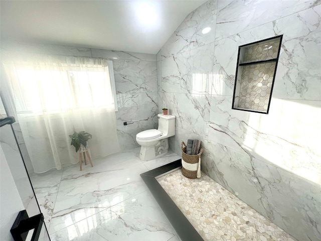 bathroom featuring lofted ceiling, marble finish floor, toilet, and stone wall