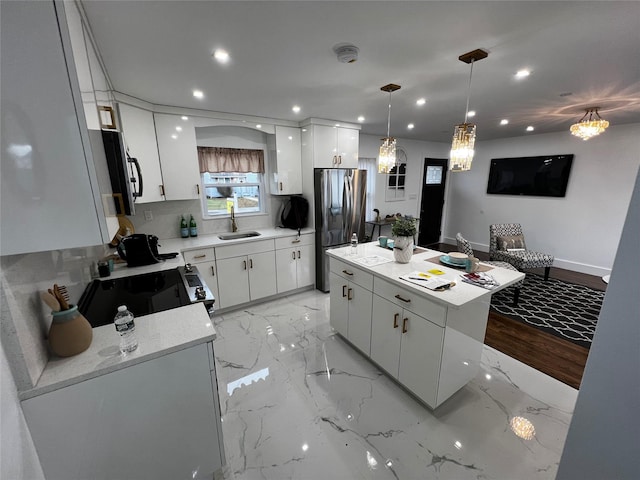 kitchen with white cabinets, a kitchen island, appliances with stainless steel finishes, light countertops, and a sink