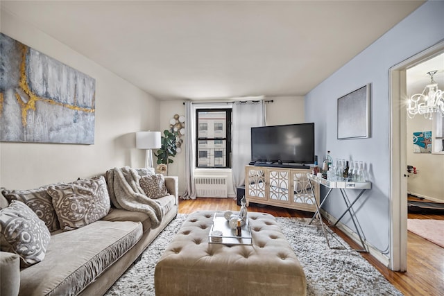 living room with radiator heating unit, hardwood / wood-style floors, and an inviting chandelier