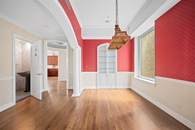 interior space with wood-type flooring, decorative columns, and ornamental molding