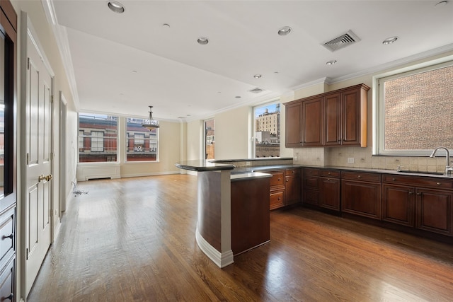 kitchen with kitchen peninsula, pendant lighting, hardwood / wood-style floors, and sink