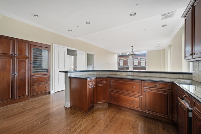 kitchen featuring decorative backsplash, dark hardwood / wood-style flooring, kitchen peninsula, and ornamental molding