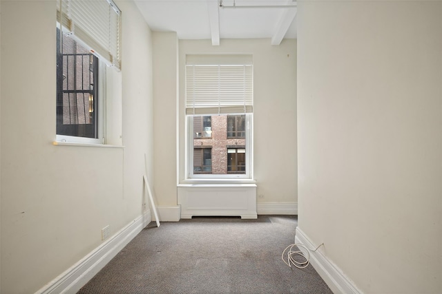 carpeted spare room featuring beam ceiling