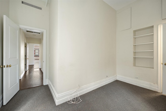 hallway featuring built in shelves and dark carpet