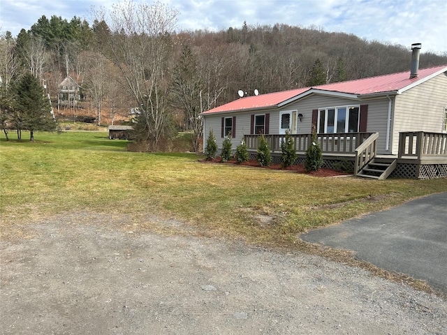 manufactured / mobile home featuring a front lawn and a wooden deck