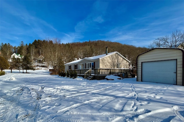 snow covered property with a garage, an outdoor structure, and a deck