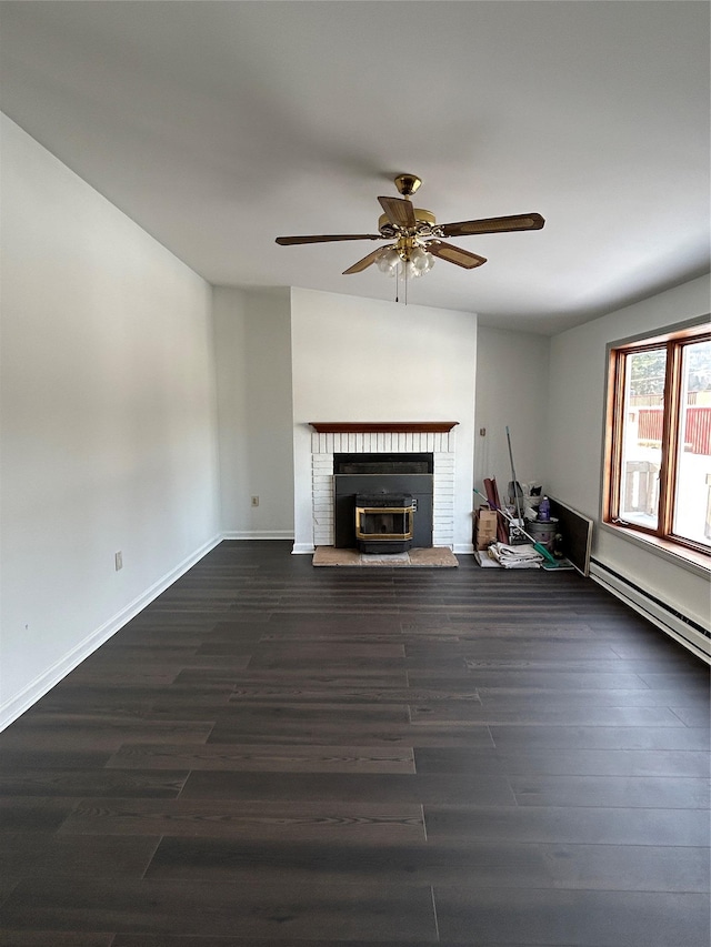 unfurnished living room featuring ceiling fan, dark hardwood / wood-style flooring, baseboard heating, and a brick fireplace