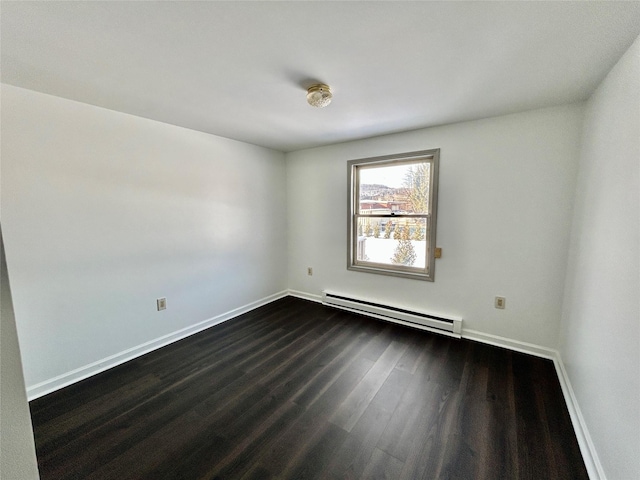 spare room featuring dark hardwood / wood-style flooring and a baseboard heating unit