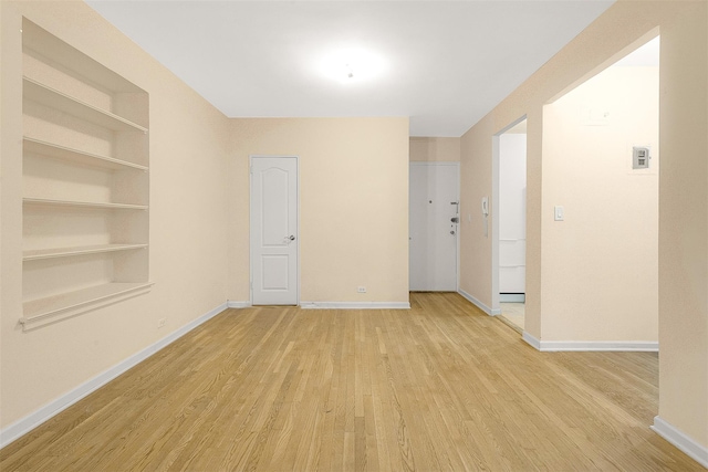 spare room featuring light hardwood / wood-style floors and built in features