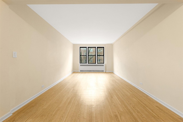 empty room with radiator heating unit and light wood-type flooring