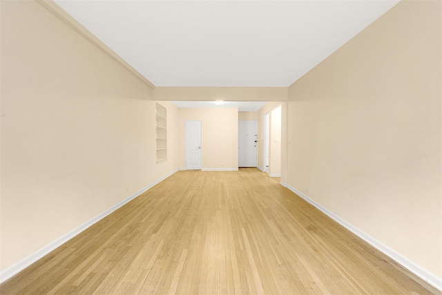 spare room with built in shelves and light hardwood / wood-style flooring