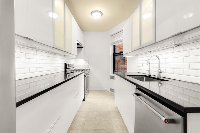 kitchen with appliances with stainless steel finishes, extractor fan, sink, dark stone countertops, and white cabinetry