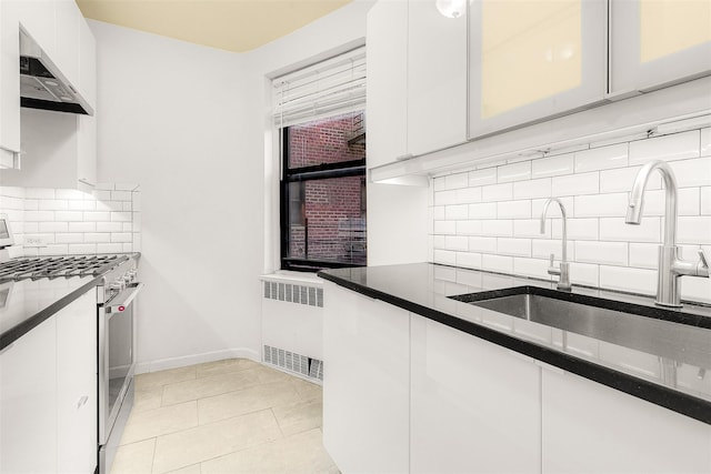 kitchen with ventilation hood, sink, white cabinets, radiator heating unit, and stainless steel range with gas cooktop