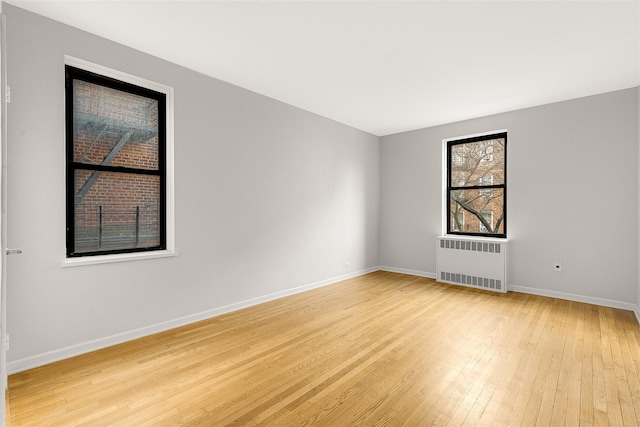 spare room featuring radiator and light wood-type flooring